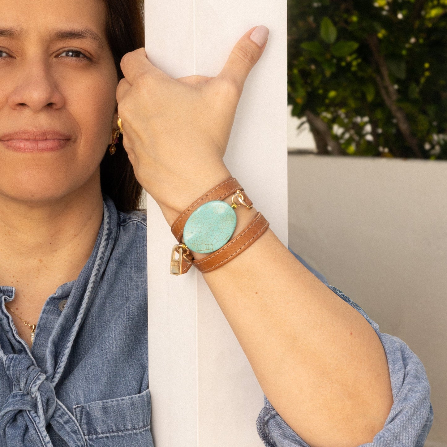 Woman wearing a genuine camel leather bracelet  with a turquoise stone, standing outdoors.