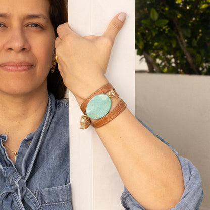Woman wearing a genuine camel leather bracelet  with a turquoise stone, standing outdoors.